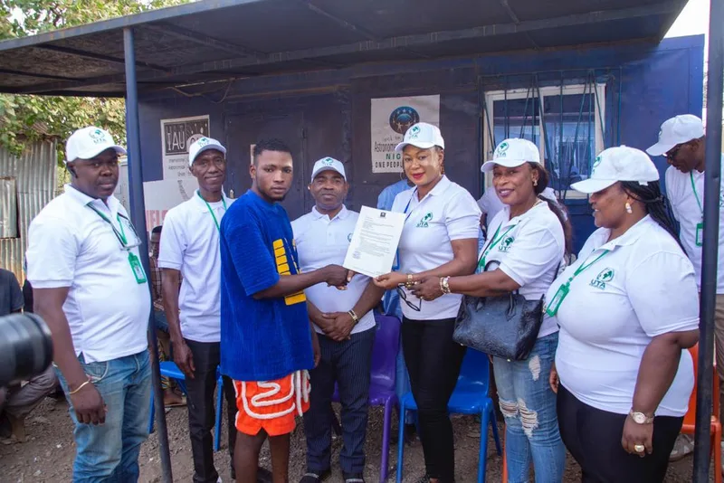 Members of a UTA team handing a document to a resident, with others looking on.